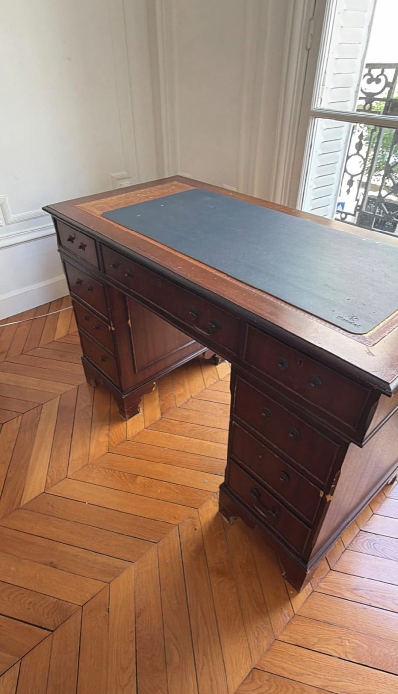 Bureau ministre ancien en acajou à caissons, plateau gainé de cuir bleu, dans un intérieur haussmannien.