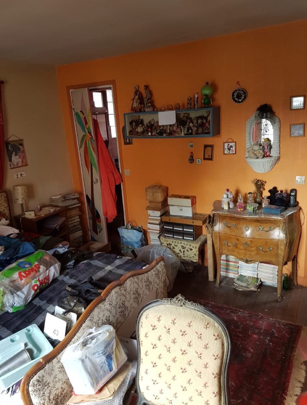 Intérieur encombré à débarrasser avec commode bombée ancienne, fauteuils Louis XV et bibelots de collection