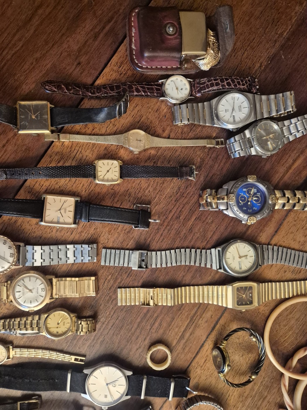 Lot de montres-bracelets anciennes en métal doré et cuir, présentées sur une table en bois