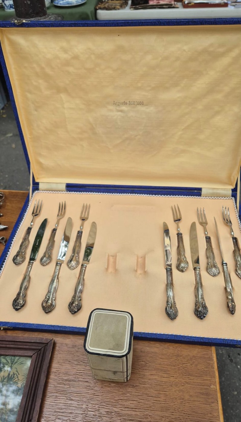 Ménagère de couverts anciens à manches en argent massif, poinçon « Argento 800 », présentée dans son écrin bleu.