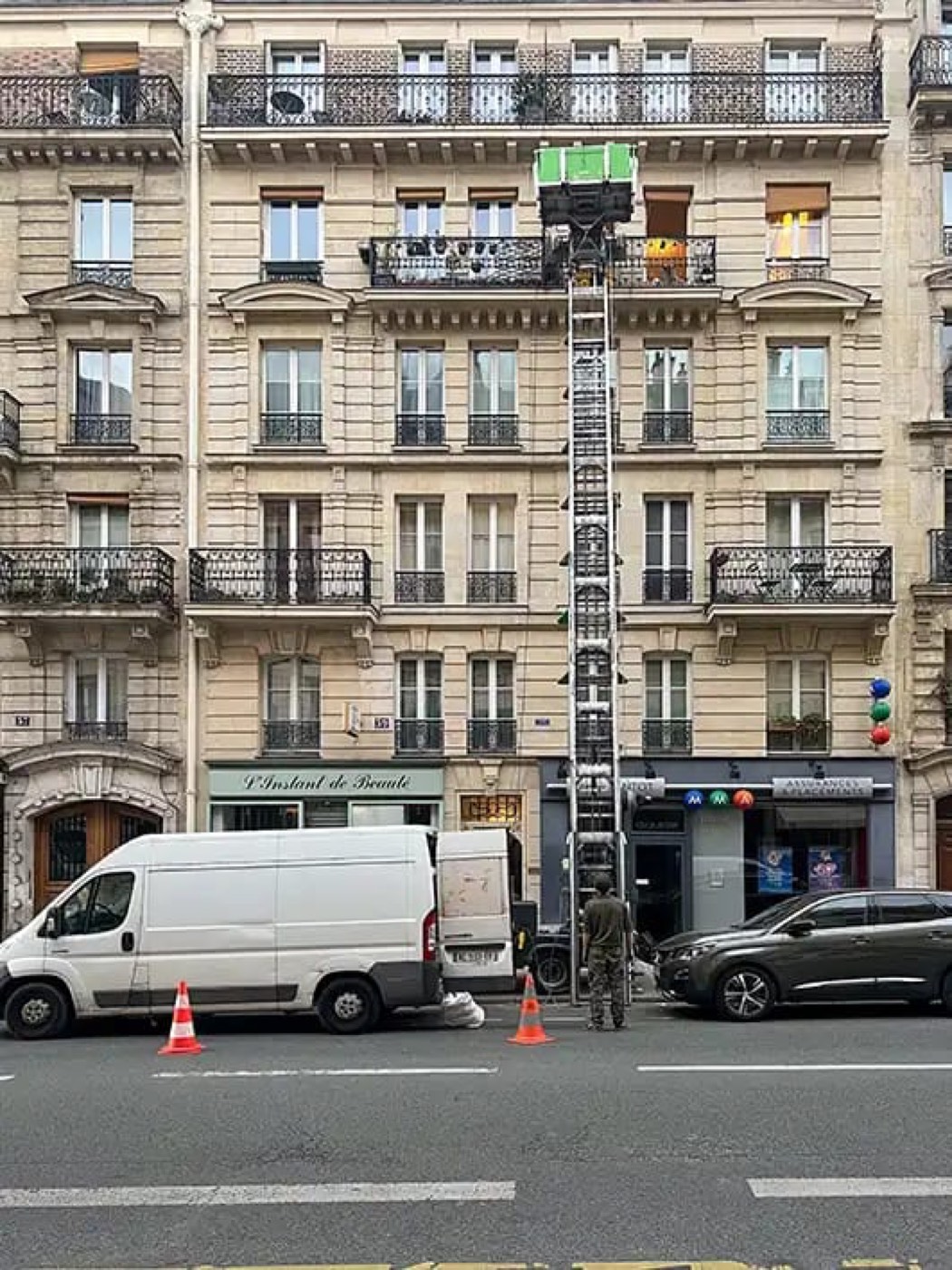 Monte-meuble hissé le long de la façade d'un immeuble parisien pour un débarras d'appartement en étage
