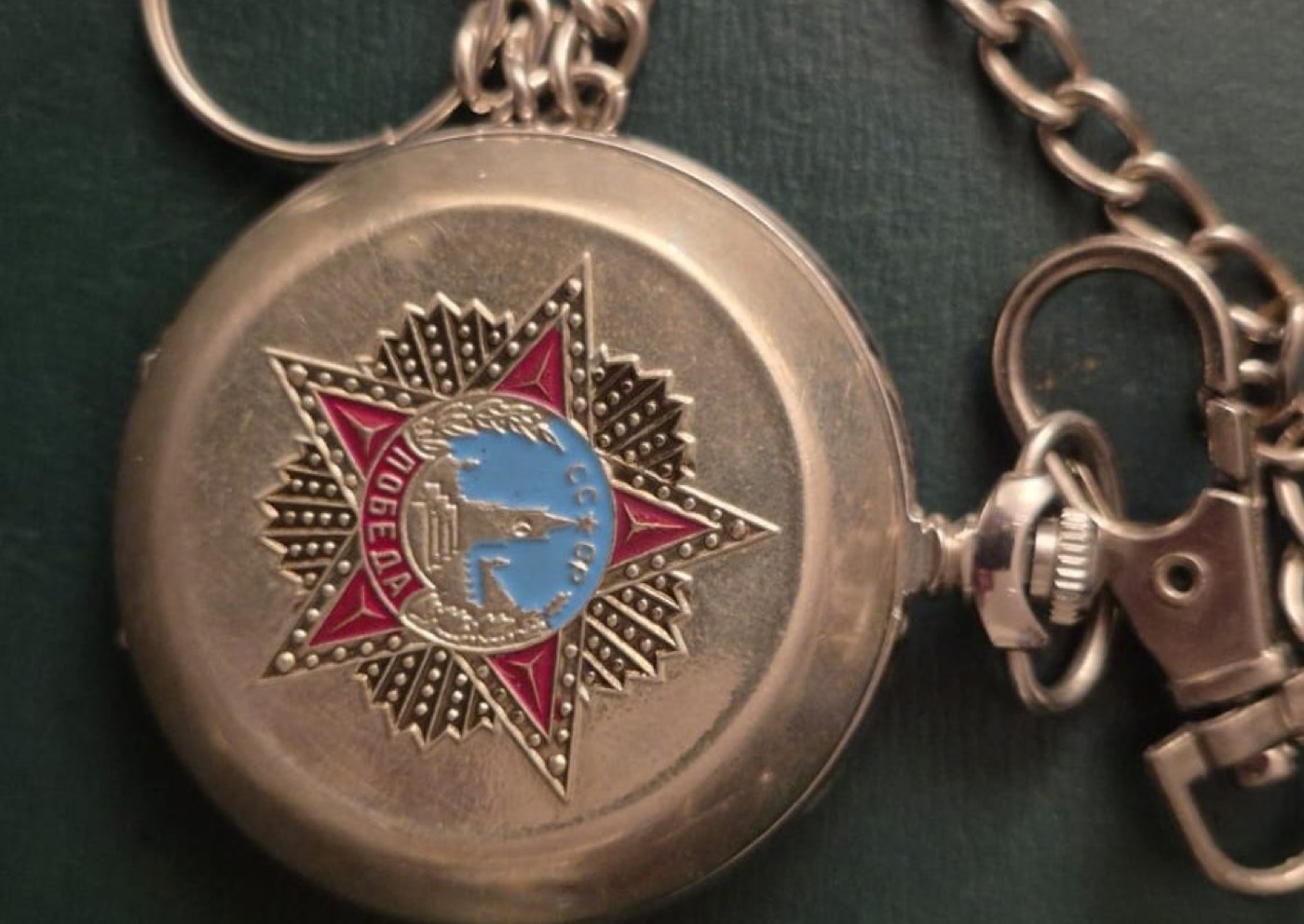 Montre de gousset ancienne en métal argenté ornée d'une étoile émaillée soviétique, présentée avec sa chaîne.