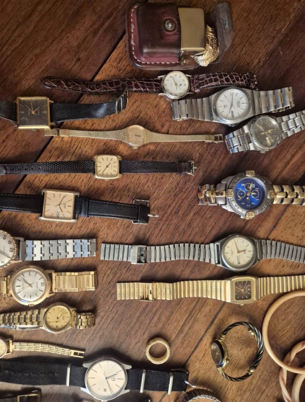 Collection de montres anciennes à bracelets cuir et métal disposées sur un plateau en bois