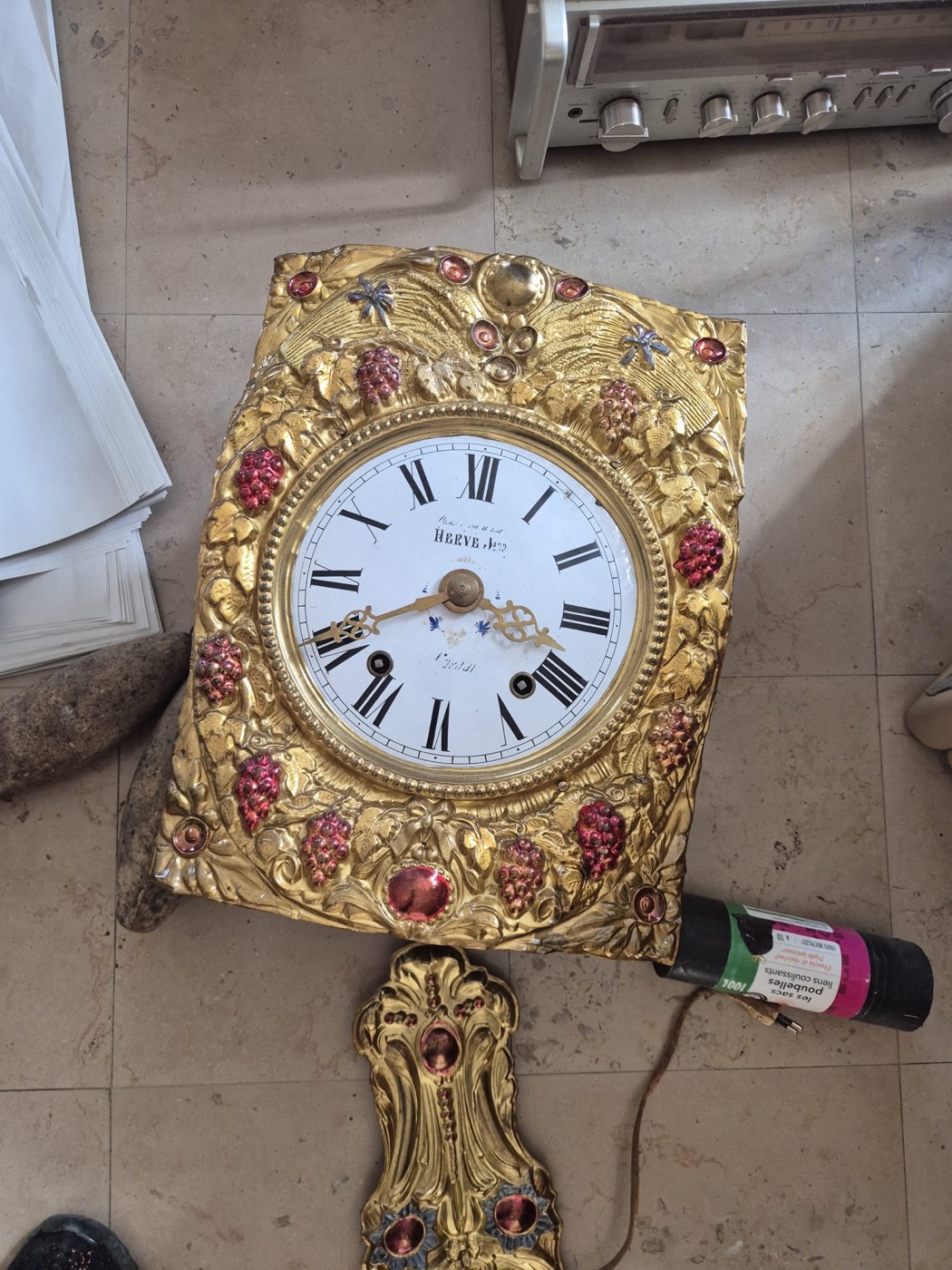 Façade en laiton repoussé et cadran émaillé d'une pendule comtoise ancienne à décor de raisins