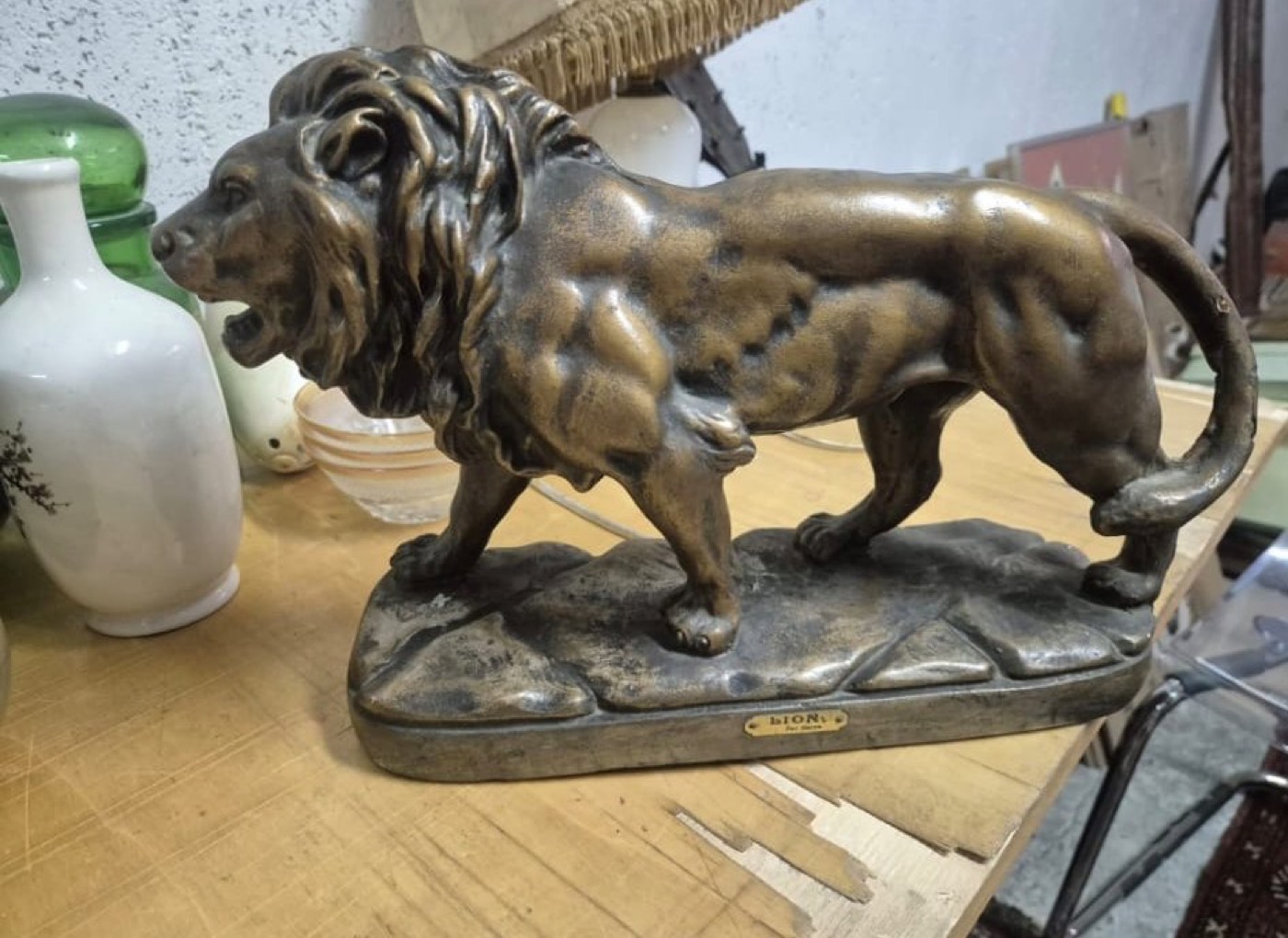 Sculpture ancienne représentant un lion rugissant en bronze patiné sur socle, avec plaque titrée « Lion ».