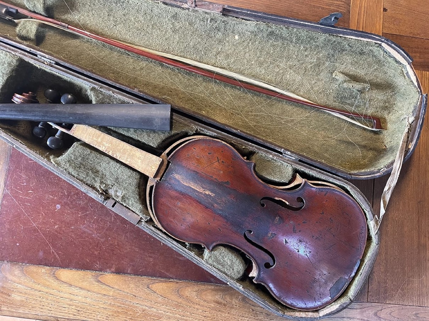 Violon ancien au vernis rougeâtre patiné rangé avec son archet dans son étui ancien